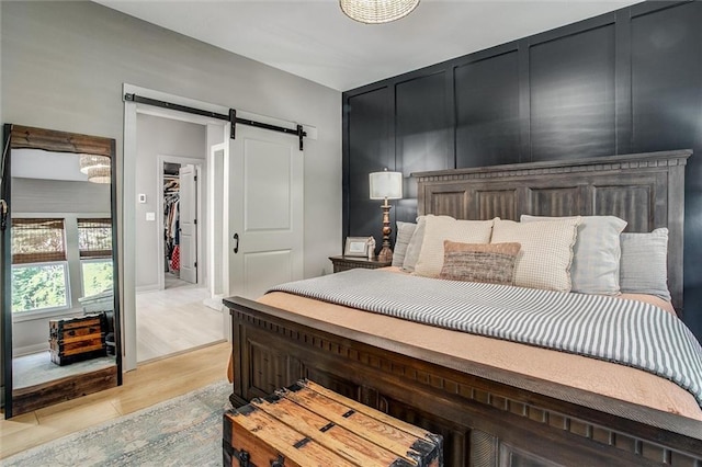 11809 E Ridgeview Ct, Peculiar, MO 64078 - bedroom with a barn door, a walk in closet, light wood-style flooring, and a closet