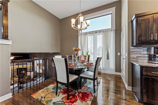 4108 NW 76th St, Kansas City, MO 64151 - dining space with dark wood-style flooring, a chandelier, baseboards, a warm lit fireplace, and high vaulted ceiling