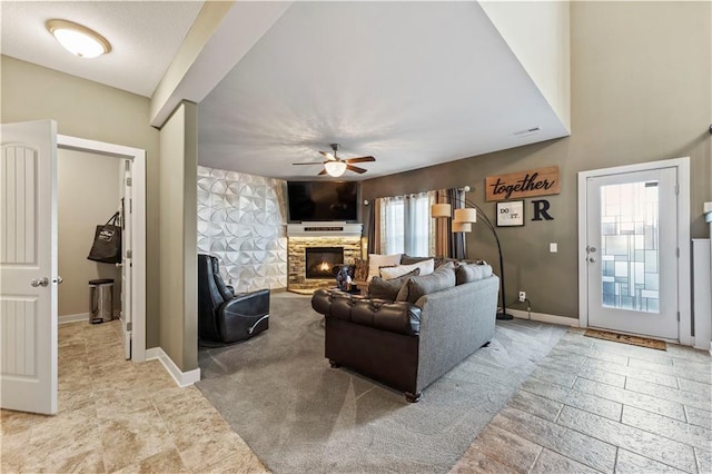 4108 NW 76th St, Kansas City, MO 64151 - living room with ceiling fan, a stone fireplace, baseboards, and stone finish floors