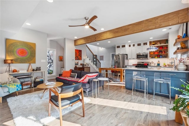 living area featuring recessed lighting, a ceiling fan, beamed ceiling, light wood finished floors, and stairs