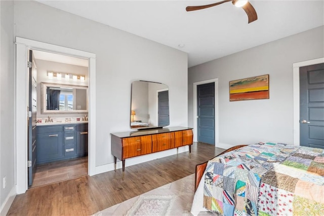 bedroom with wood finished floors, baseboards, ensuite bathroom, and a ceiling fan