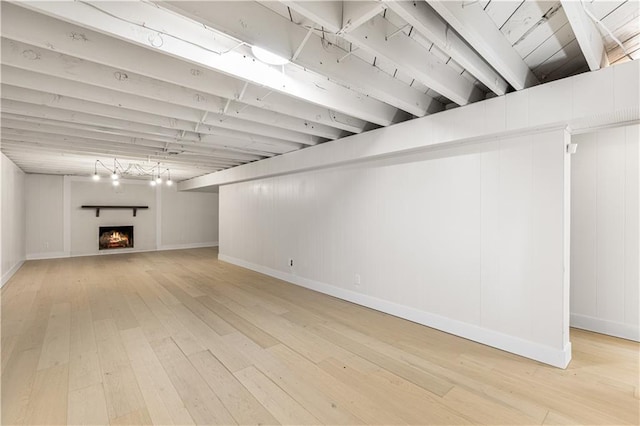 218 NW 43rd Ter, Kansas City, MO 64116 - below grade area with light wood-style floors, baseboards, and a lit fireplace