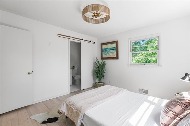 218 NW 43rd Ter, Kansas City, MO 64116 - bedroom featuring a barn door and light wood-style flooring