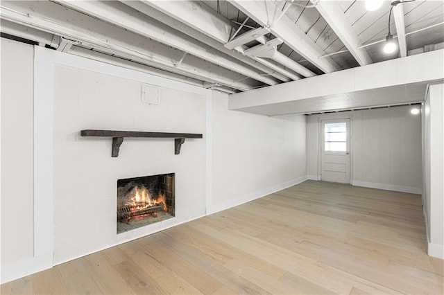 218 NW 43rd Ter, Kansas City, MO 64116 - below grade area featuring a fireplace, light wood-style floors, and baseboards