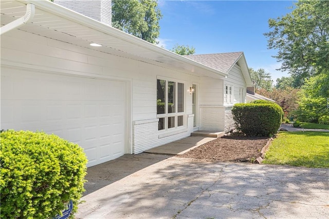 218 NW 43rd Ter, Kansas City, MO 64116 - view of property exterior with an attached garage, a chimney, brick siding, concrete driveway, and a shingled roof