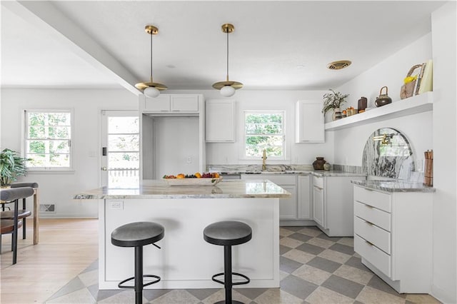 218 NW 43rd Ter, Kansas City, MO 64116 - kitchen with light floors, a kitchen breakfast bar, open shelves, white cabinetry, and light stone counters