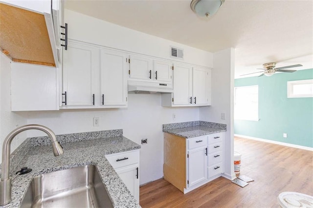 6021 E 151st Ter, Grandview, MO 64030 - kitchen featuring a sink, under cabinet range hood, a ceiling fan, white cabinetry, and light stone counters