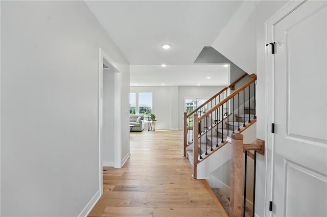 hallway with light wood finished floors, stairs, recessed lighting, and baseboards