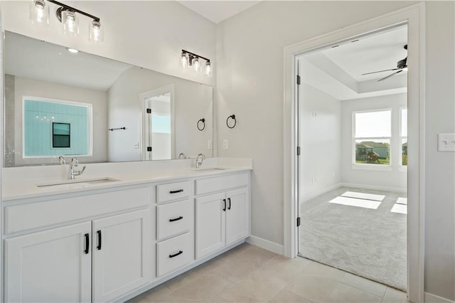 full bath featuring a ceiling fan, double vanity, baseboards, tile patterned floors, and a tray ceiling