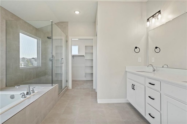 bathroom with a stall shower, vanity, a garden tub, tile patterned flooring, and baseboards
