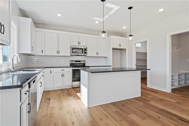 kitchen featuring appliances with stainless steel finishes, a sink, white cabinets, light wood-style floors, and recessed lighting