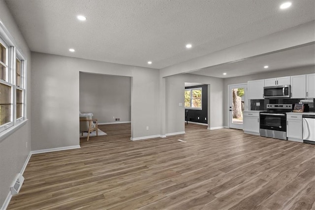 unfurnished living room with a textured ceiling, light wood-style flooring, baseboards, and recessed lighting