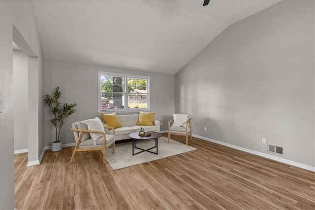 sitting room featuring vaulted ceiling, light wood finished floors, baseboards, and a ceiling fan