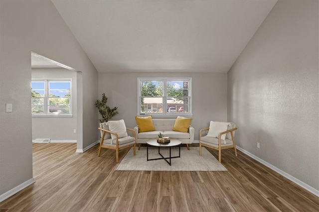 living area with vaulted ceiling, wood finished floors, and baseboards