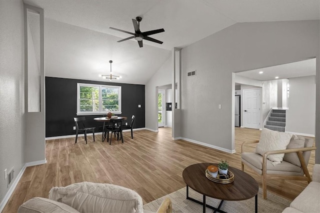 living room with lofted ceiling, light wood-style flooring, stairs, a ceiling fan, and baseboards