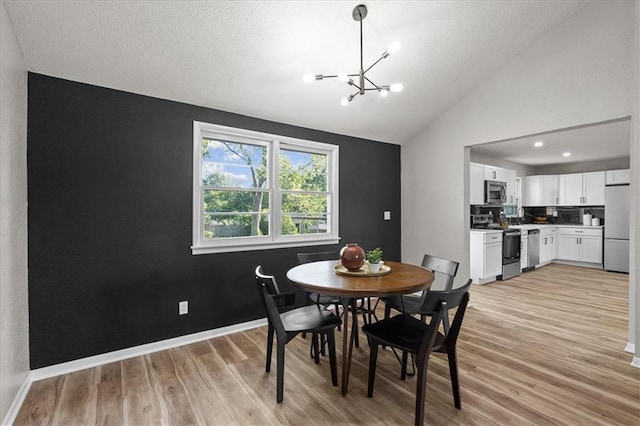 dining room with a chandelier, light wood finished floors, lofted ceiling, and baseboards