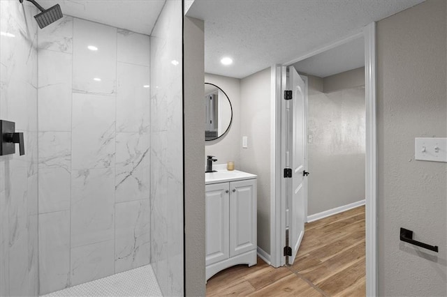 bathroom featuring tiled shower, wood finished floors, vanity, a textured ceiling, and recessed lighting