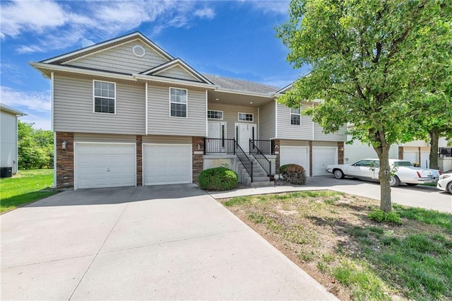 bi-level home featuring a garage, driveway, and central air condition unit