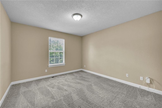 unfurnished room with carpet flooring, baseboards, and a textured ceiling