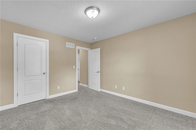 unfurnished bedroom with carpet flooring, baseboards, and a textured ceiling