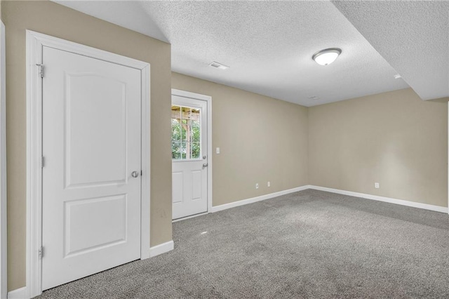 carpeted empty room featuring a textured ceiling and baseboards