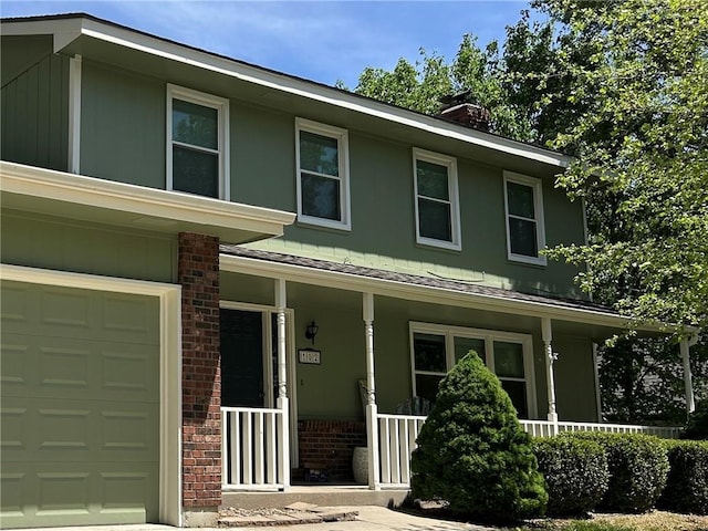 102 Willow Pt, Lansing, KS 66043 - view of front of home featuring covered porch, brick siding, a chimney, and a garage