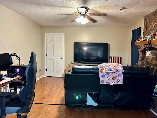 102 Willow Pt, Lansing, KS 66043 - living room featuring ceiling fan, wood finished floors, a textured ceiling, a desk, and a brick fireplace