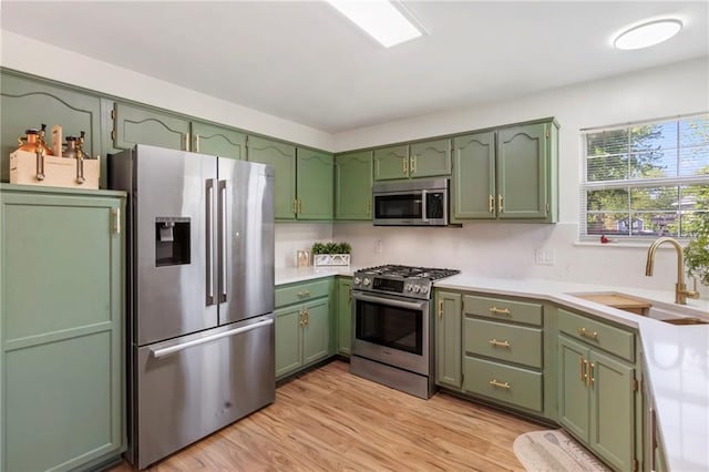 kitchen with green cabinets, appliances with stainless steel finishes, a sink, and light countertops