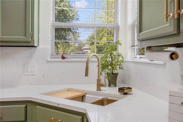 kitchen view of green cabinetry, a sink, and tasteful backsplash