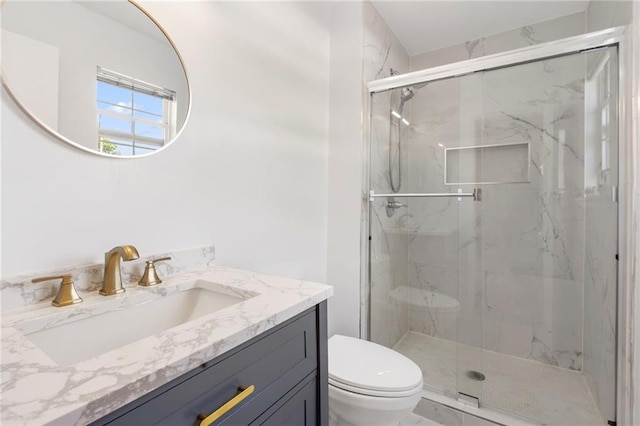 full bathroom featuring toilet, a marble finish shower, and vanity