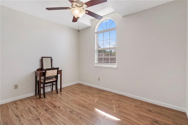 spare room featuring wood finished floors, baseboards, and a ceiling fan