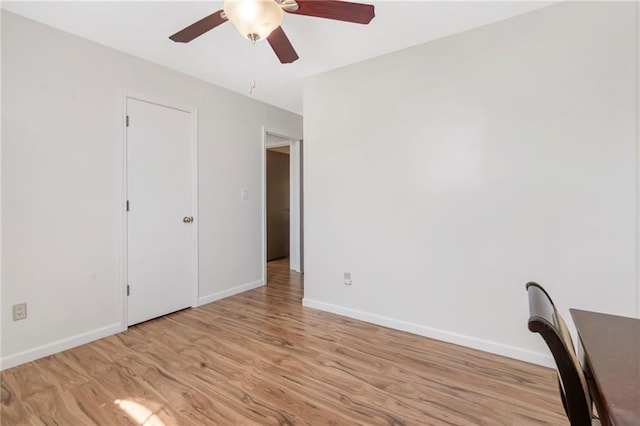 unfurnished office featuring a ceiling fan, light wood finished floors, and baseboards