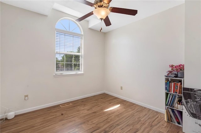 empty room with wood finished floors, baseboards, and a ceiling fan