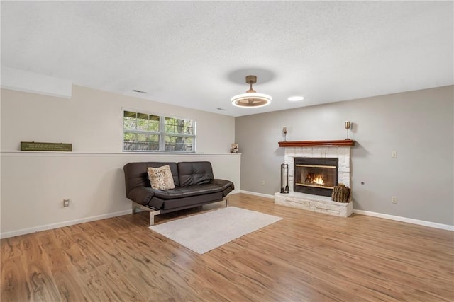 living area with wood finished floors, a textured ceiling, and baseboards