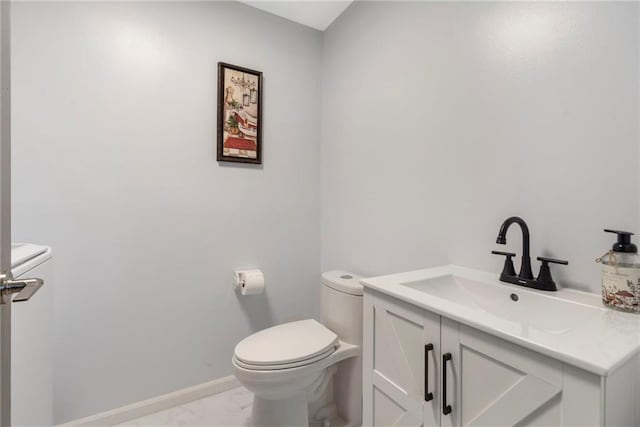 half bathroom featuring toilet, marble finish flooring, vanity, and baseboards