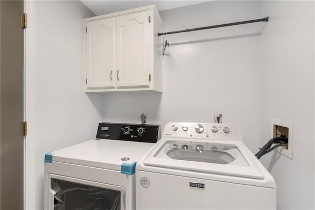 clothes washing area featuring cabinet space and washing machine and clothes dryer
