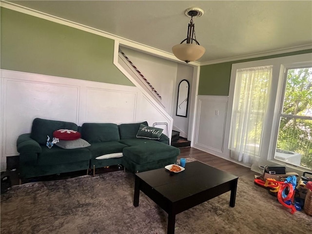 living room featuring a decorative wall, stairway, a wainscoted wall, crown molding, and wood finished floors