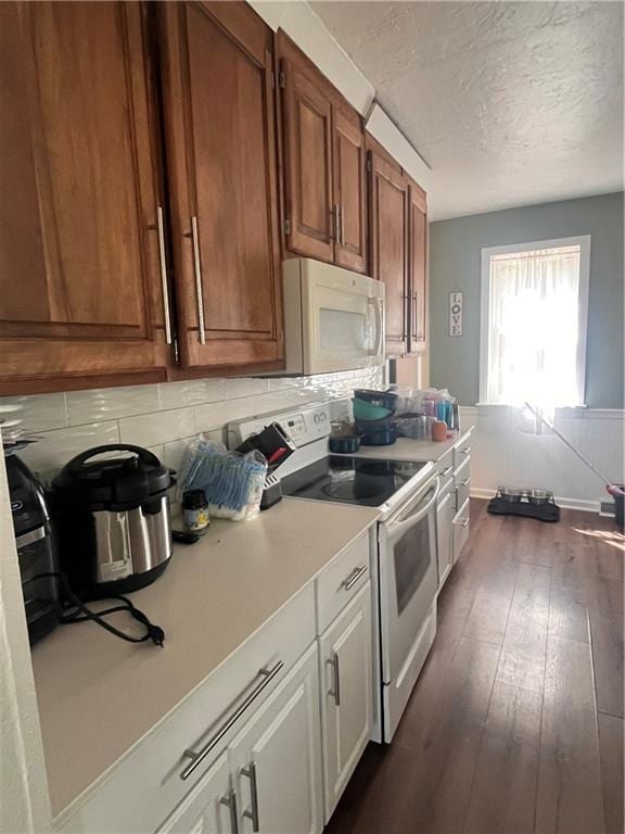 kitchen featuring white appliances, light countertops, dark wood-style flooring, decorative backsplash, and a textured ceiling