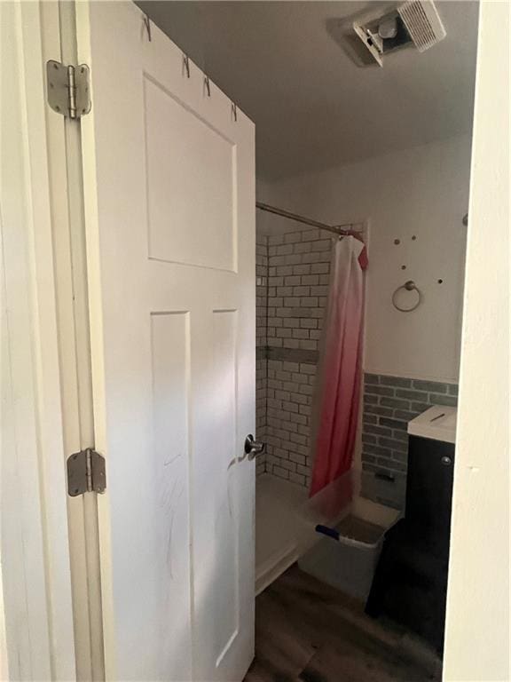 bathroom featuring curtained shower and wood finished floors