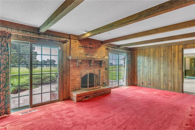 28210 Hedge Ln, Paola, KS 66071 - unfurnished living room featuring wood walls, a textured ceiling, plenty of natural light, carpet, and beamed ceiling