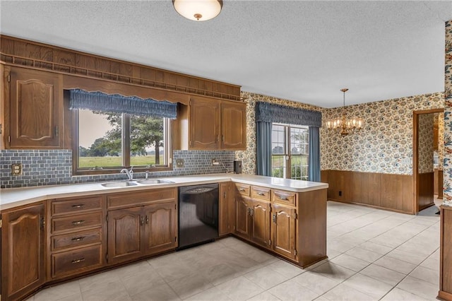 28210 Hedge Ln, Paola, KS 66071 - kitchen featuring black dishwasher, a sink, a peninsula, a chandelier, and wainscoting