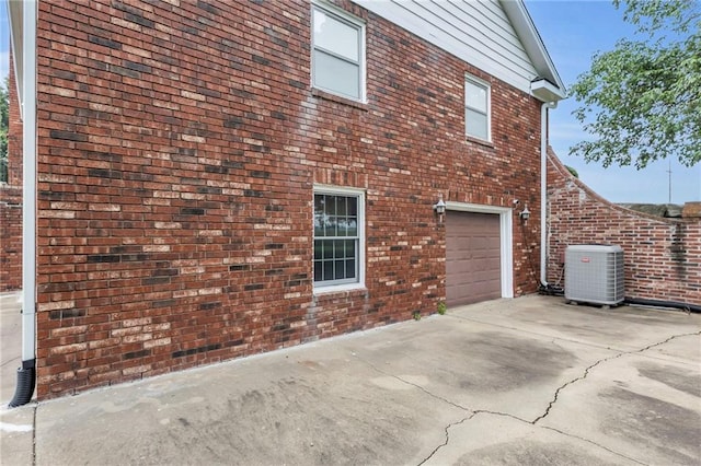 28210 Hedge Ln, Paola, KS 66071 - view of side of property featuring central AC unit, brick siding, a garage, and concrete driveway