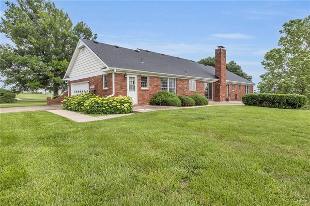 28210 Hedge Ln, Paola, KS 66071 - single story home with a chimney, brick siding, a front yard, and an attached garage