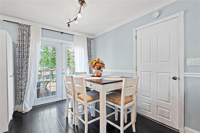 dining room with dark wood-style flooring, crown molding, and rail lighting
