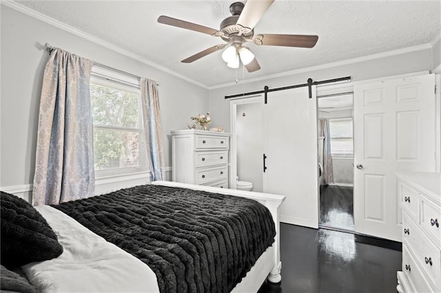 bedroom featuring a barn door, dark wood-type flooring, ornamental molding, and ceiling fan