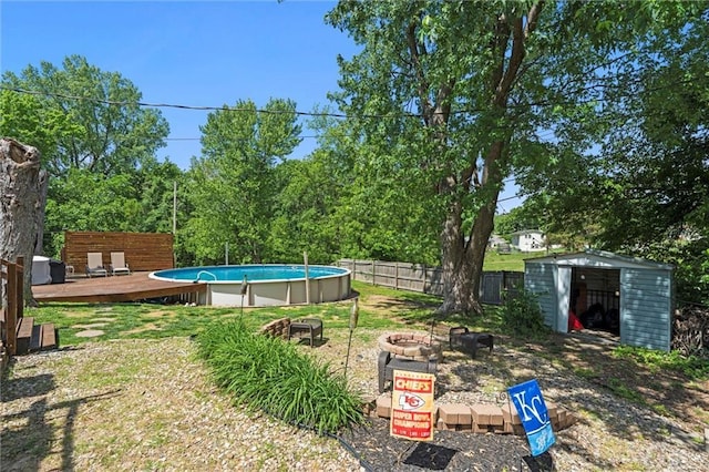 view of yard with a fire pit, a storage unit, a deck, fence, and an outbuilding