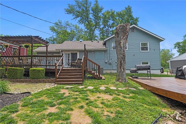 back of property with a pergola, a deck, and a lawn