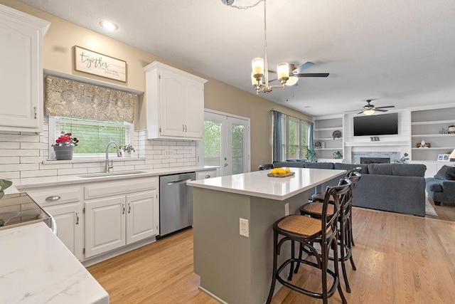 14263 W 129th Ter, Olathe, KS 66062 - kitchen with stainless steel dishwasher, a sink, open floor plan, a breakfast bar area, and white cabinets