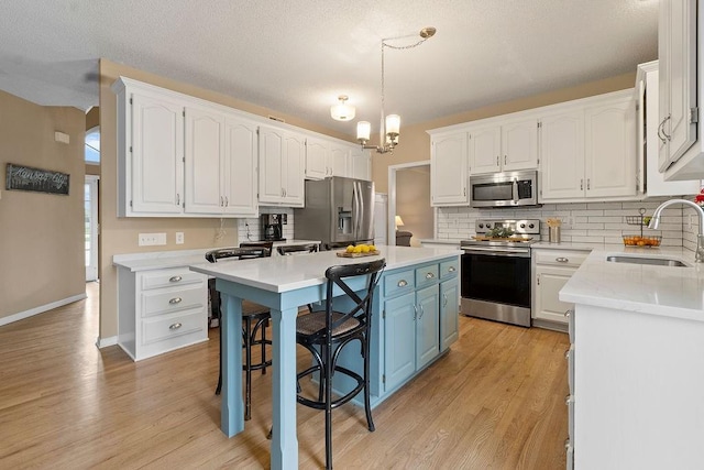 14263 W 129th Ter, Olathe, KS 66062 - kitchen with a sink, stainless steel appliances, white cabinets, and blue cabinetry