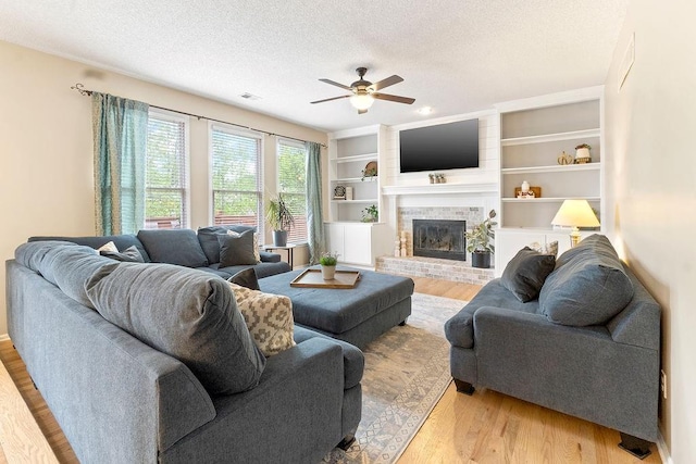 14263 W 129th Ter, Olathe, KS 66062 - living area featuring ceiling fan, light wood-style floors, a brick fireplace, and a textured ceiling